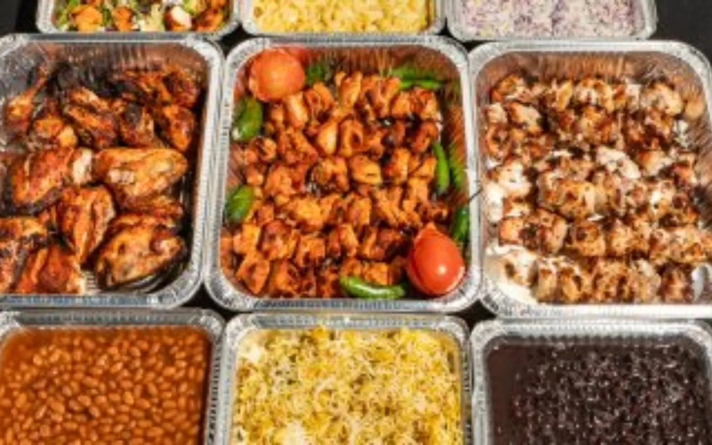 BBQ Toni8ht halal Pakistani catering trays of chicken tikka, malai boti, biryani and sides laid out for an event